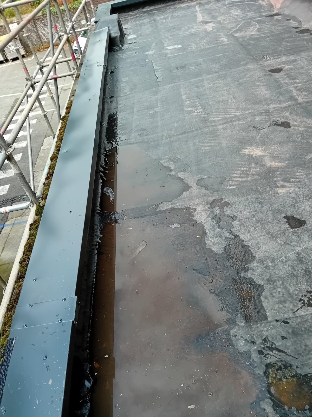 Détail d'une toiture en EPDM avec une zone d’eau stagnante le long du bord, mettant en évidence la nécessité d’une pente adaptée pour une bonne évacuation des eaux pluviales.