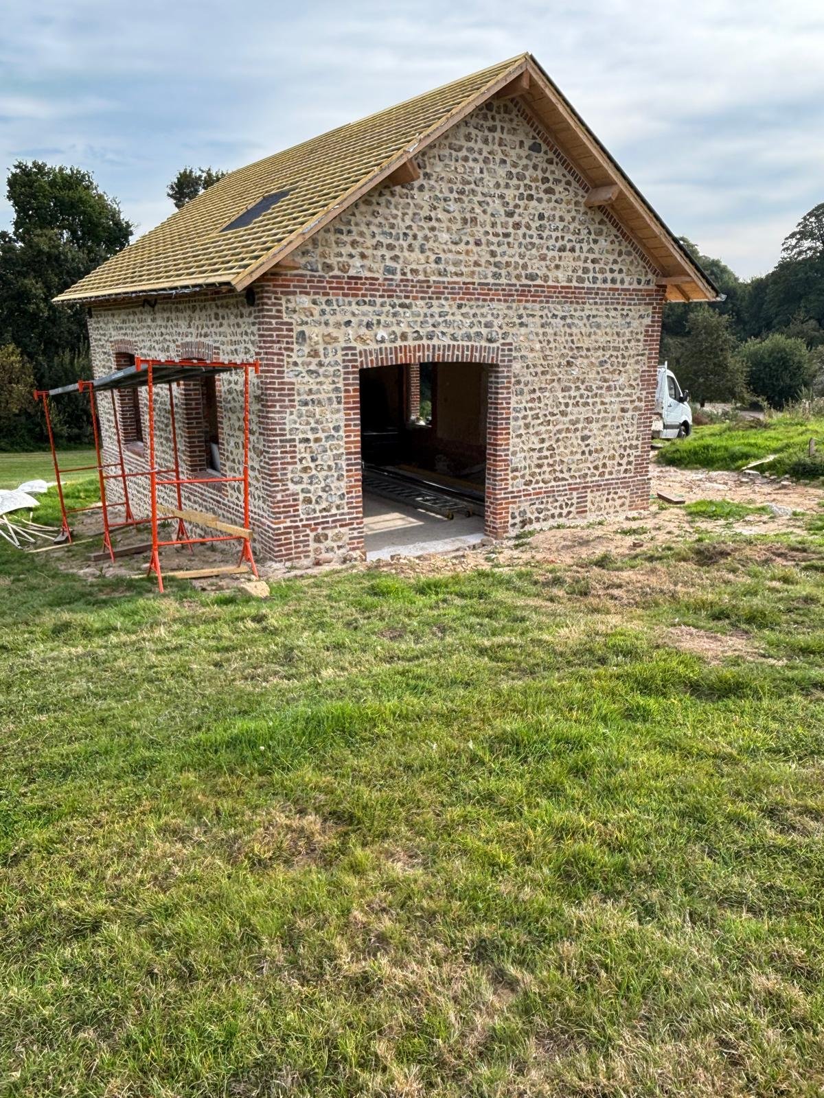 Réfection d’une toiture en ardoise sur une bâtisse normande en silex et briques.