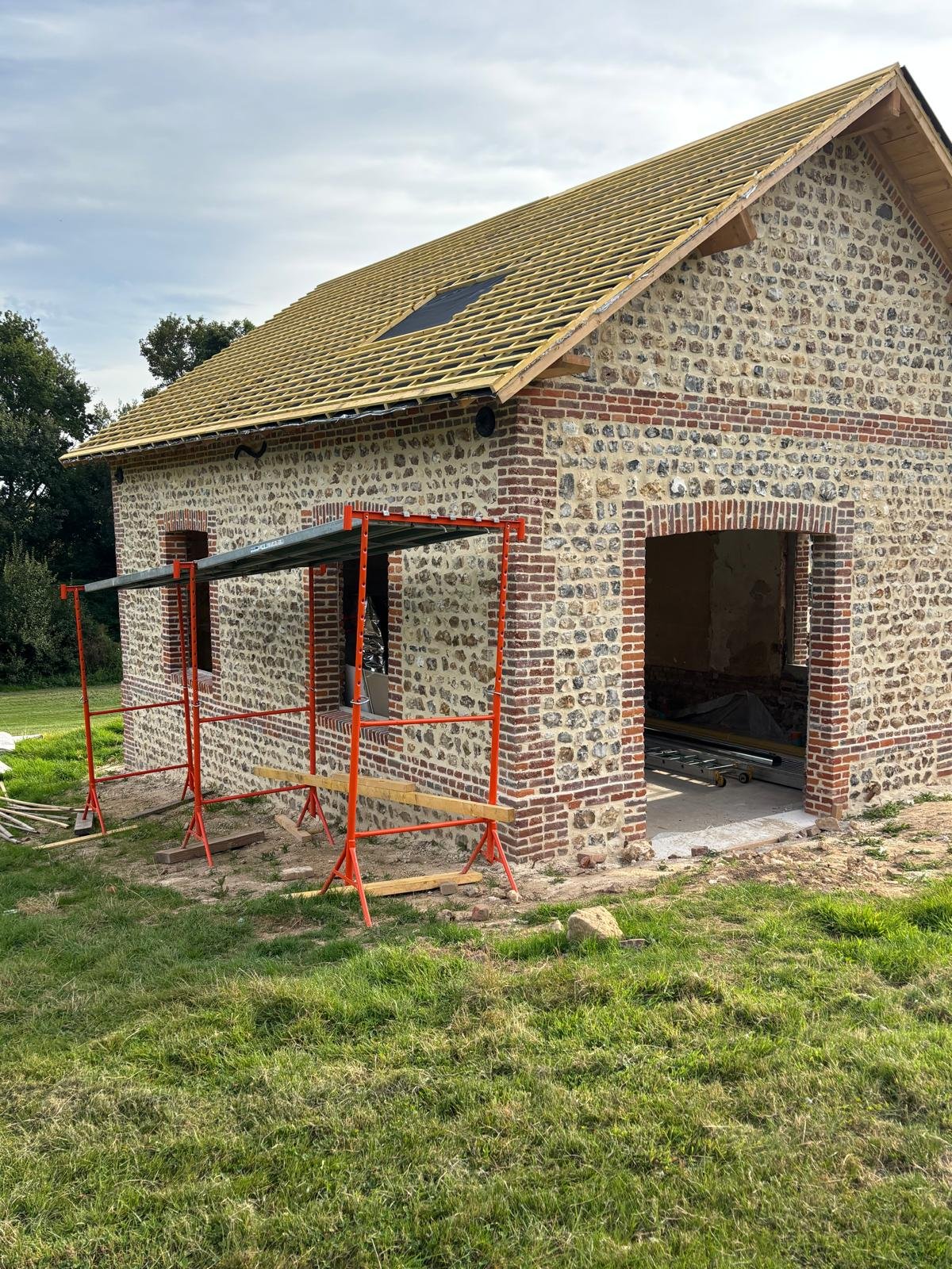 Réfection d’une toiture en ardoise sur une bâtisse normande en silex et briques.