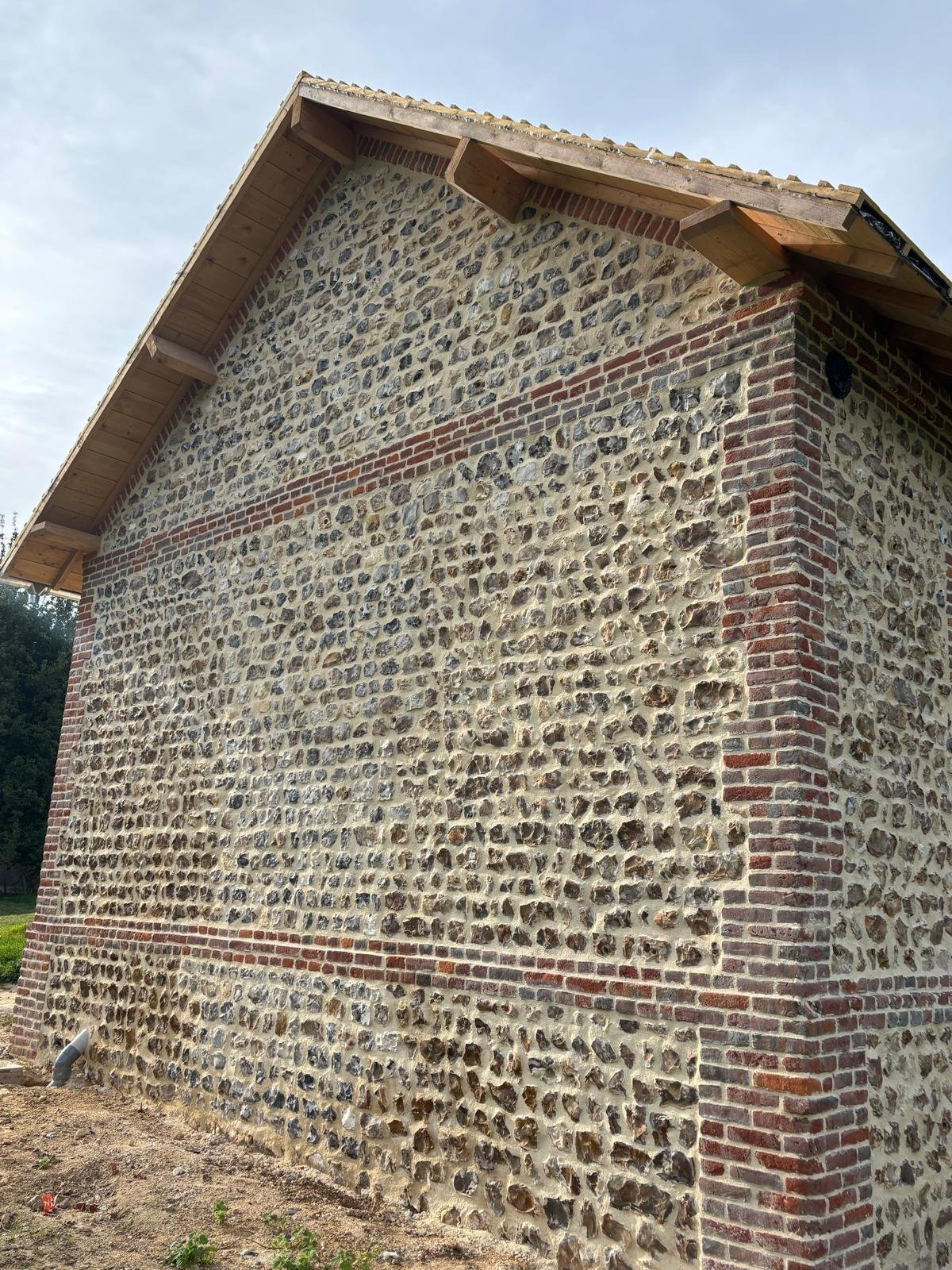 Réfection d’une toiture en ardoise sur une bâtisse normande en silex et briques.