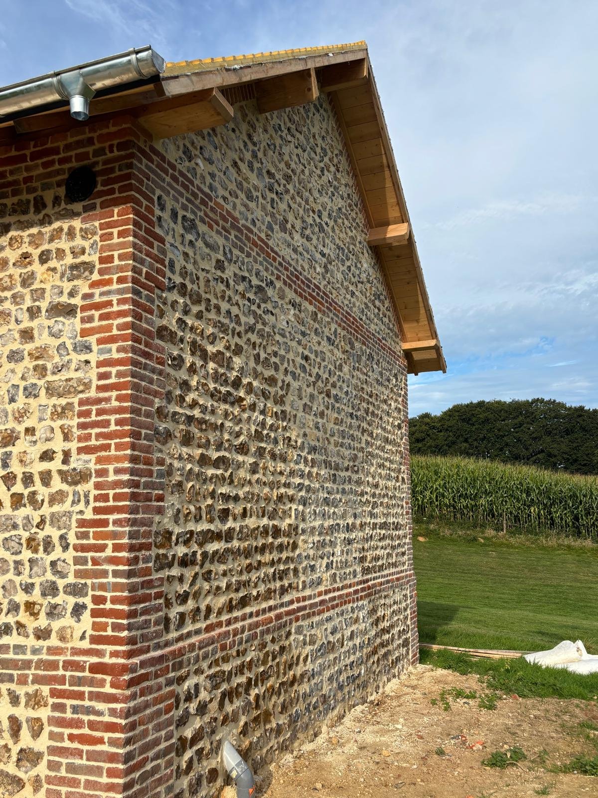 Réfection d’une toiture en ardoise sur une bâtisse normande en silex et briques.