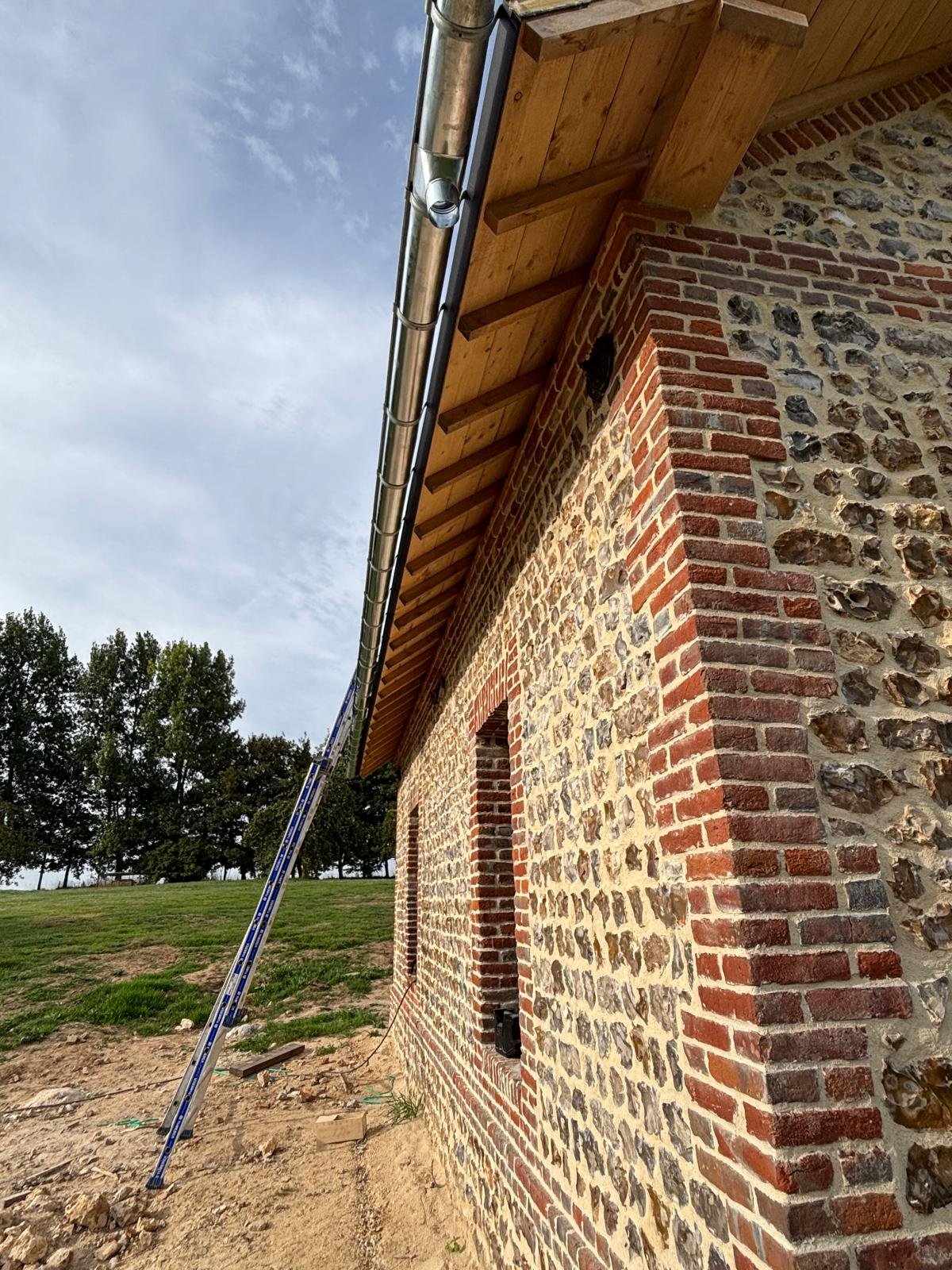 Réfection d’une toiture en ardoise sur une bâtisse normande en silex et briques.