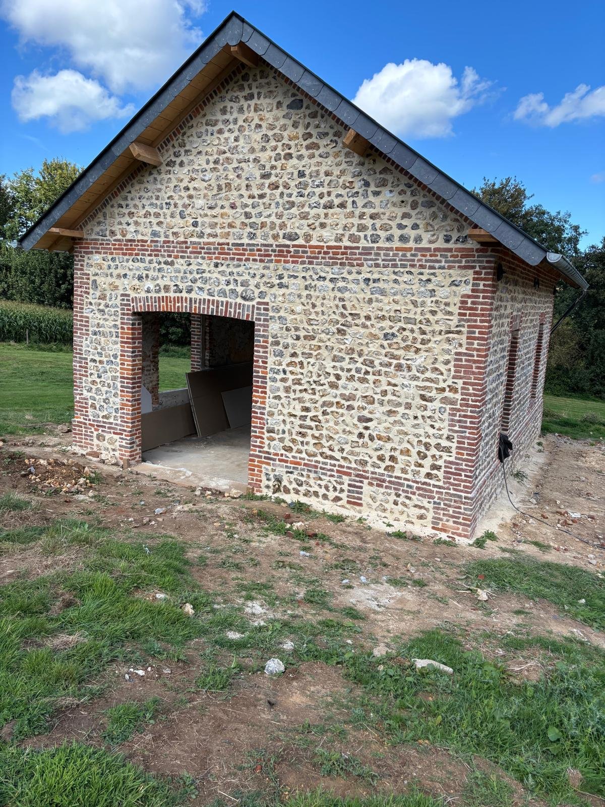 Réfection d’une toiture en ardoise sur une bâtisse normande en silex et briques.