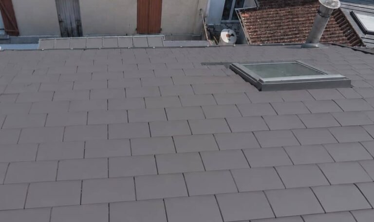 Rénovation complète d'une toiture à Rouen avec pose de tuiles plates gris anthracite, raccords d'étanchéité soignés et intégration d'une fenêtre de toit Velux.