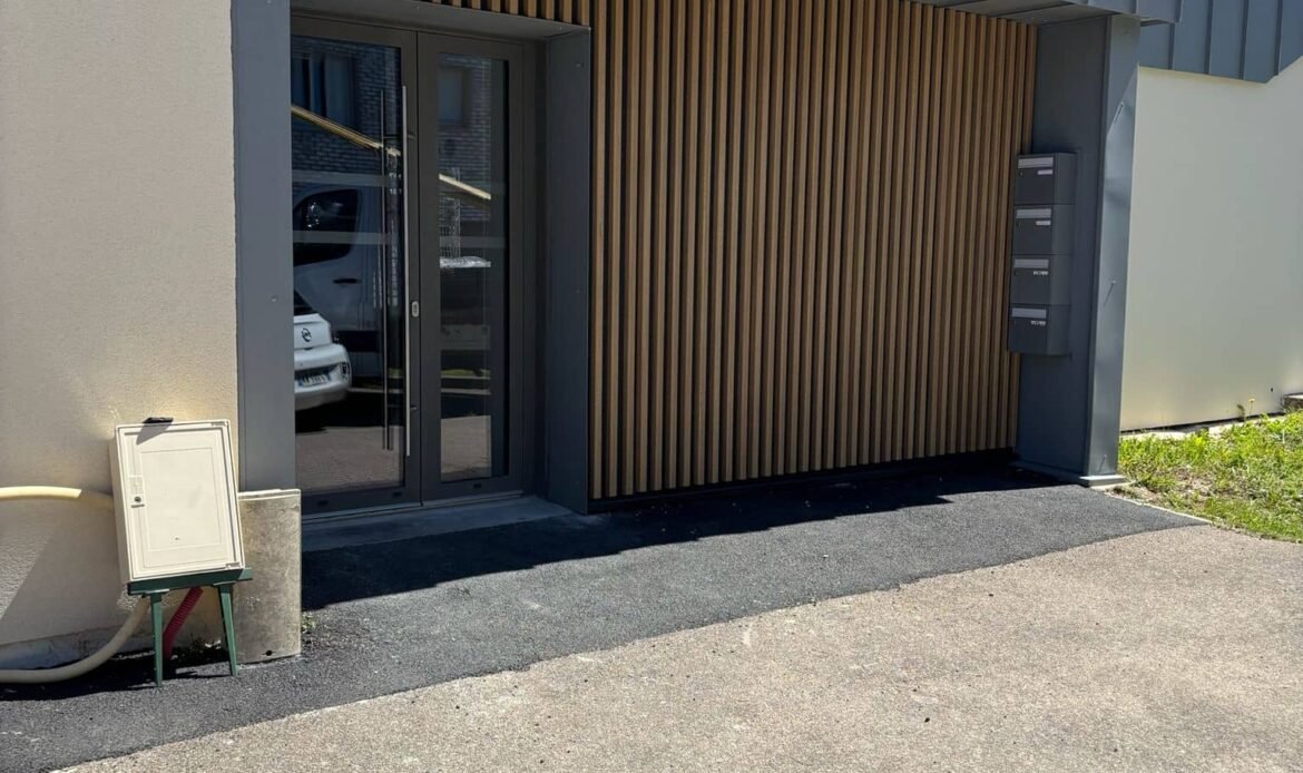 Entrée de bâtiment avec un bardage bois aspect claire-voie et des finitions en zinc à joint debout près de Rouen.