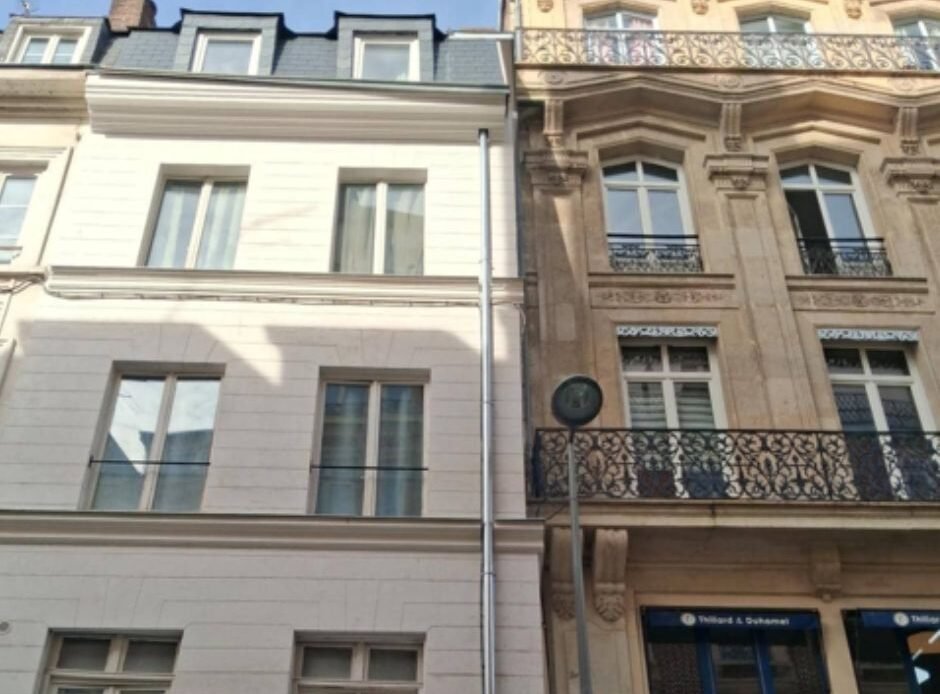 Rénovation de façade d'immeuble à Rouen avec tuyau de descente d'eau pluviale en zinc et échafaudage de chantier.