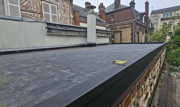 Toit terrasse EPDM terminé avec rive en aluminium noir sur mur en brique et silex à Rouen centre - CF Couverture